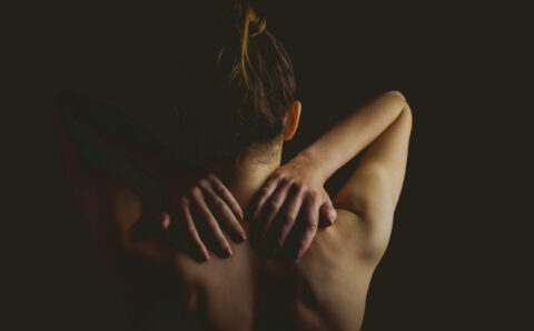 Nude woman with a neck injury on black background