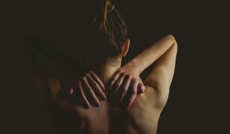 Nude woman with a neck injury on black background