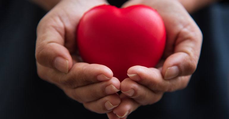 Close up hands giving red heart as heart donor. Valentine day of