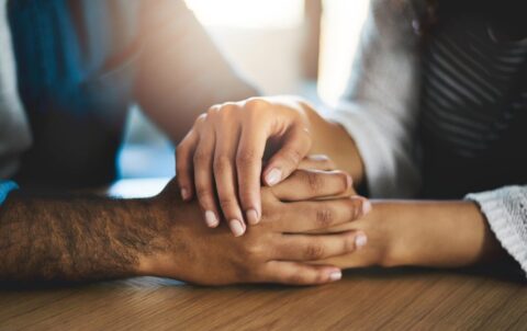 All it takes is a loving hand. a man and woman compassionately holding hands at a table.