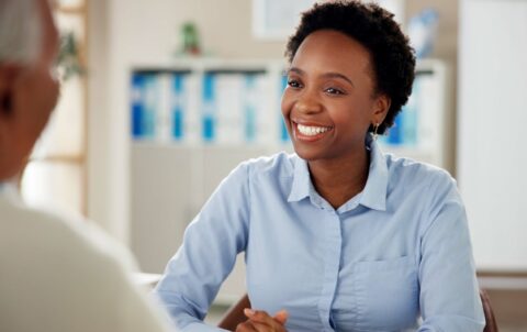 Black woman, employee and happy with senior customer at office for retirement and pension plans as financial advisor. Female person, people and smile with client as for will consultation service