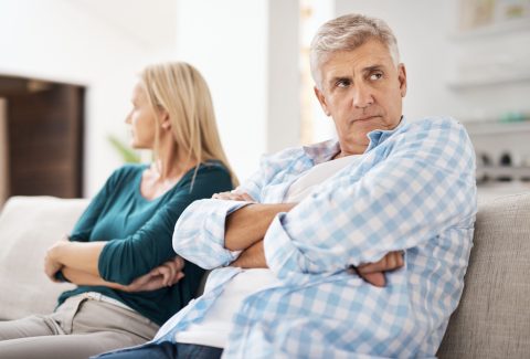 Mature, man and couple fight in home on sofa, people and domestic issue or ignore for infidelity affair. Crossed arms, frustrated and conflict in living room together, divorce and relationship drama
