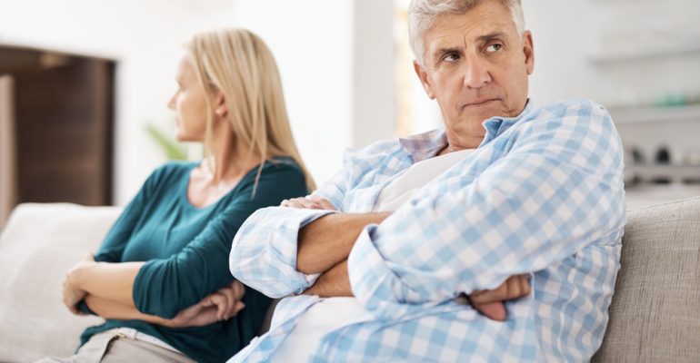 Mature, man and couple fight in home on sofa, people and domestic issue or ignore for infidelity affair. Crossed arms, frustrated and conflict in living room together, divorce and relationship drama
