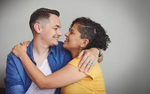 Couple, hug and happy in studio with love, affection and trust in healthy relationship. Man, woman or embrace on gray background space with support, smile or commitment in marriage for Valentines Day
