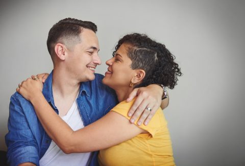 Couple, hug and happy in studio with love, affection and trust in healthy relationship. Man, woman or embrace on gray background space with support, smile or commitment in marriage for Valentines Day