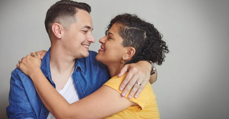 Couple, hug and happy in studio with love, affection and trust in healthy relationship. Man, woman or embrace on gray background space with support, smile or commitment in marriage for Valentines Day
